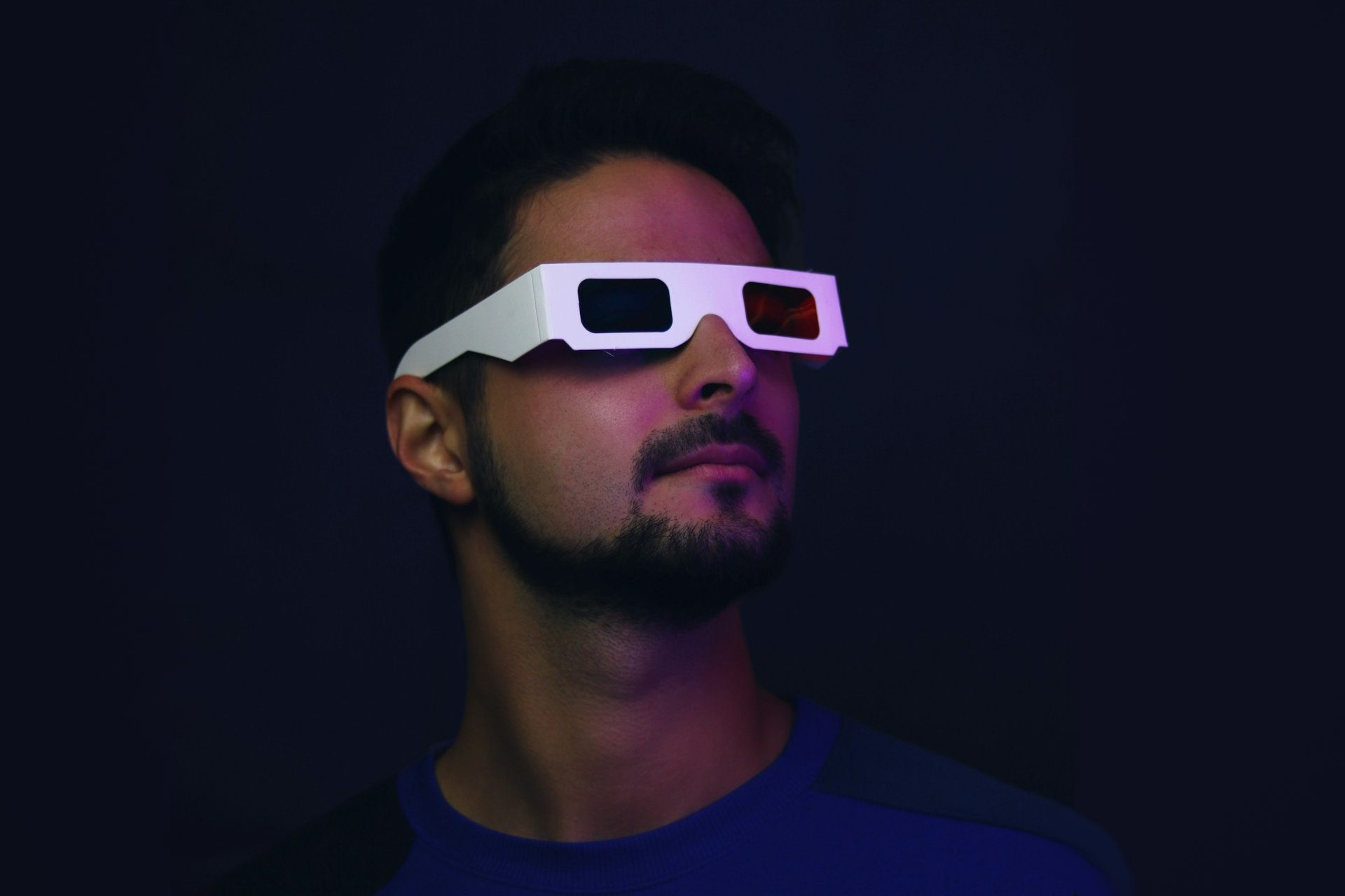 A person in a dark environment wears 3D anaglyphic glasses.