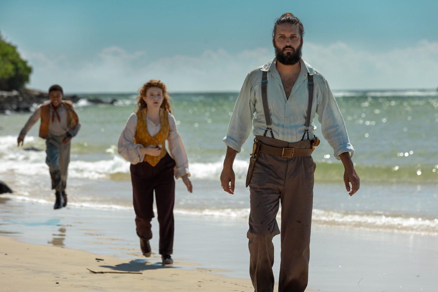 A group of people walk on the beach.