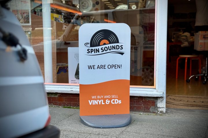 A store sign on a pavement.