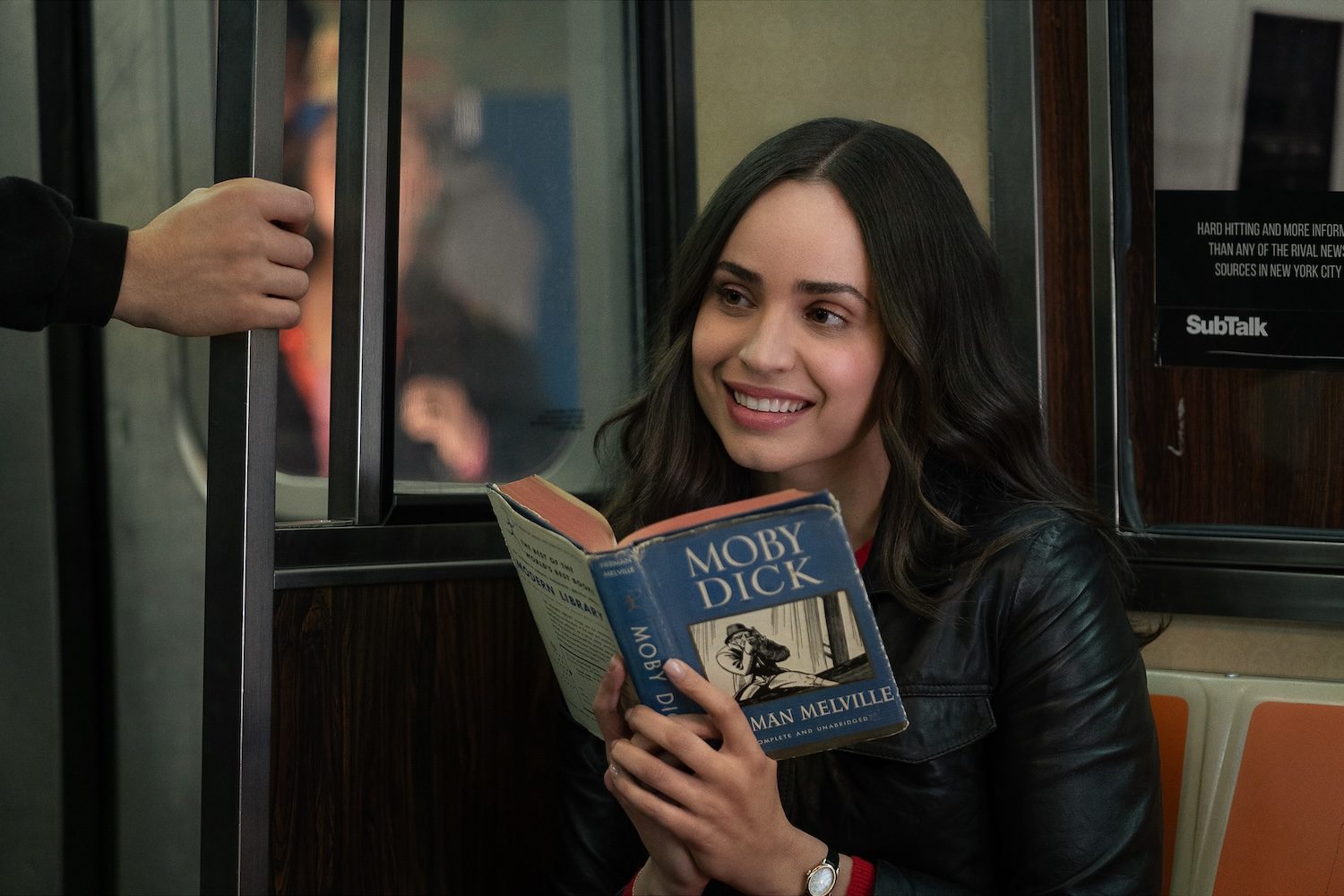 A girl holds a book on a seat.