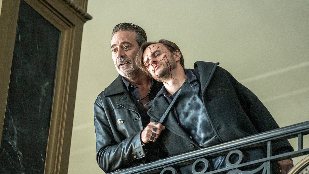 Negan holding a knife to a bloody man's throat in The Walking Dead: Dead City.