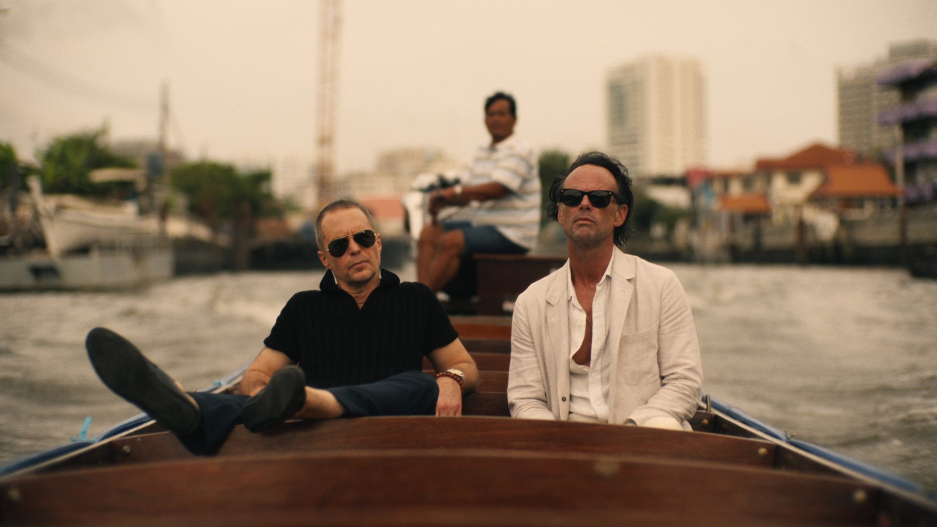 Two men sit on a boat and stare.