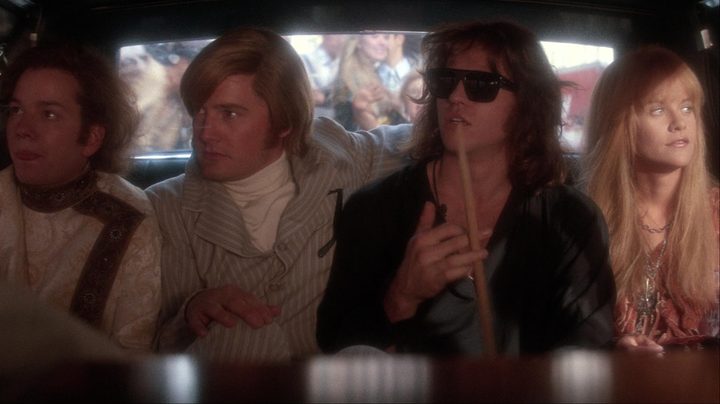 A group of band members sits in the back of a car.