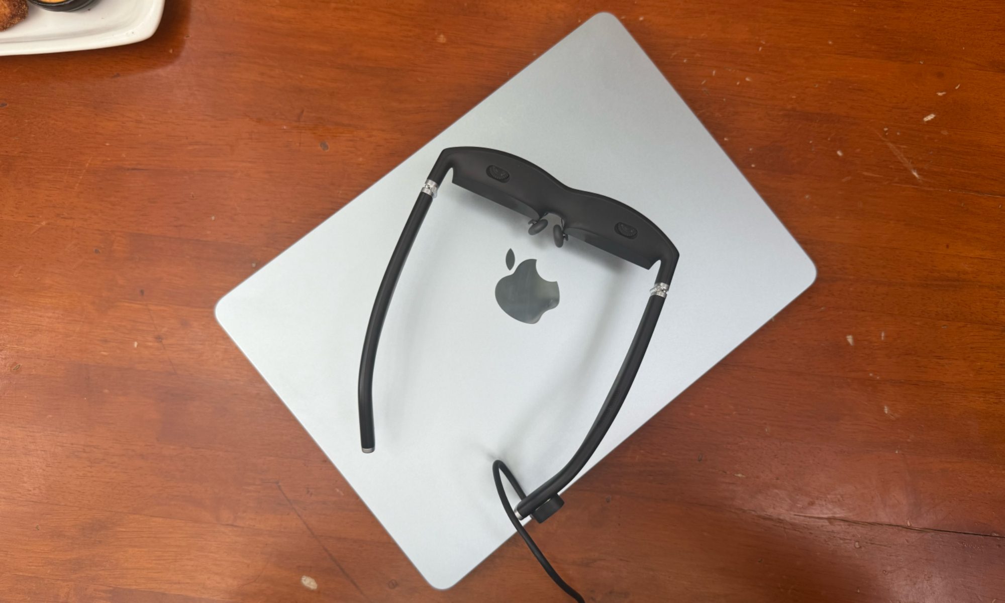 Viture One smart glasses resting on an Apple laptop.
