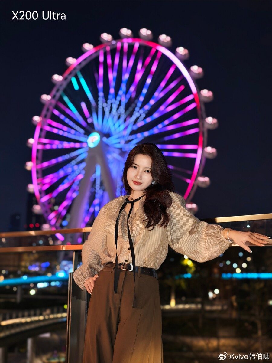 A woman stands in front of a ferris wheel