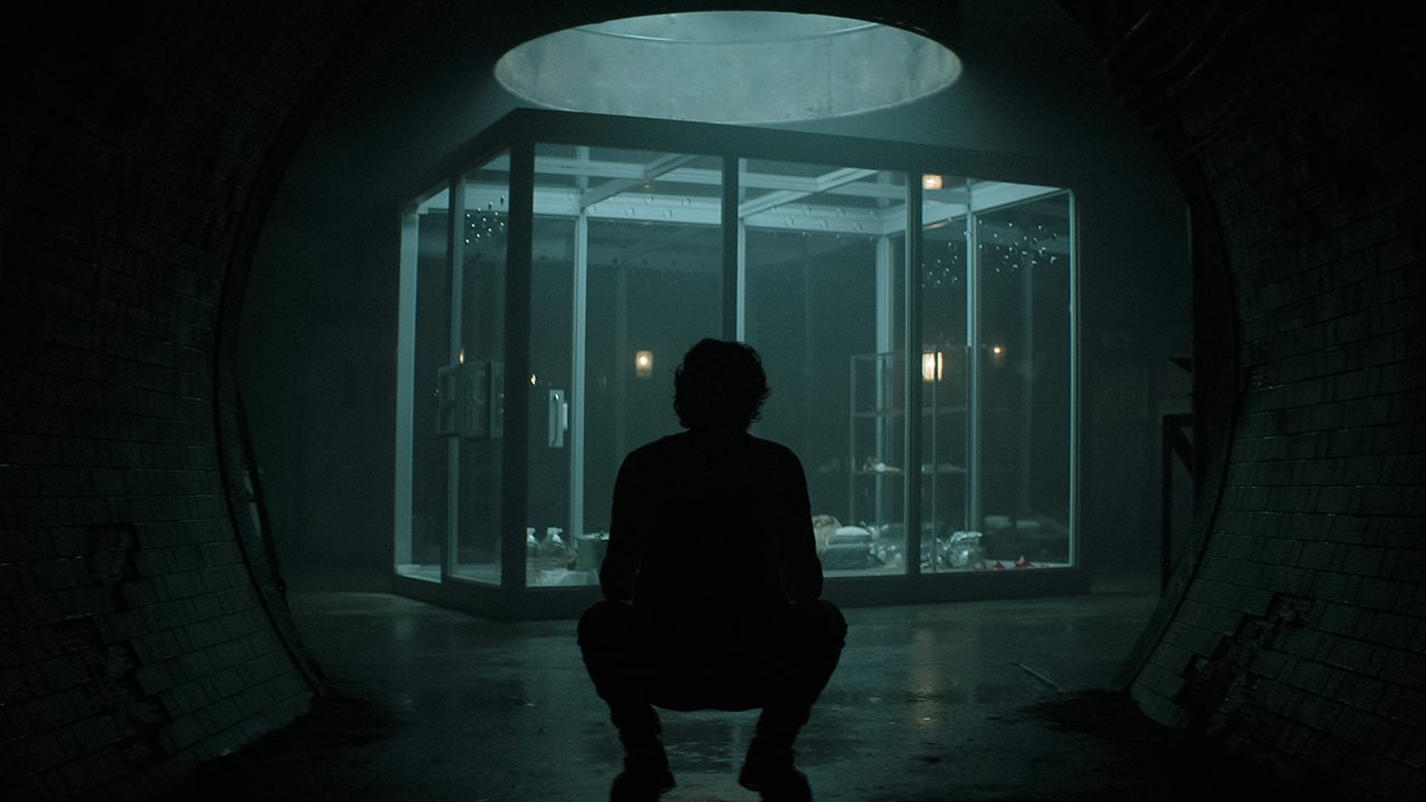Joe crouched down in front of his cage in You.