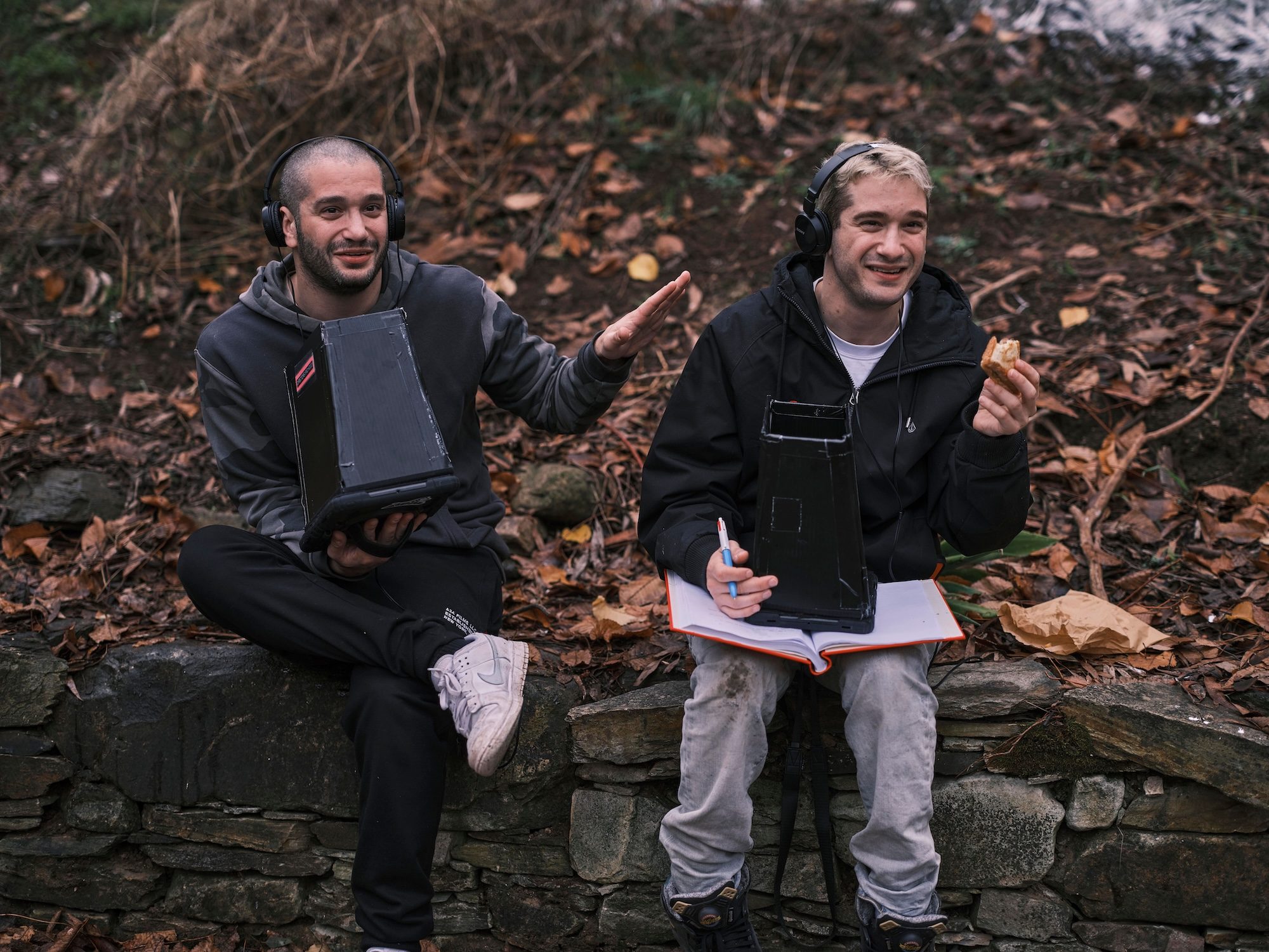 Two guys sit on a rock wall in Bring Her Back.