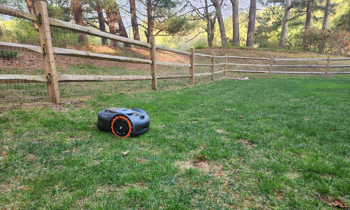 Segway Navimow i110 robot lawn mower cutting the grass inside a fenced area.