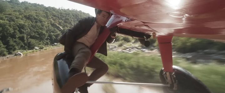 Tom Cruise hanging from a red plane in "Mission: Impossible - The Final Reckoning"