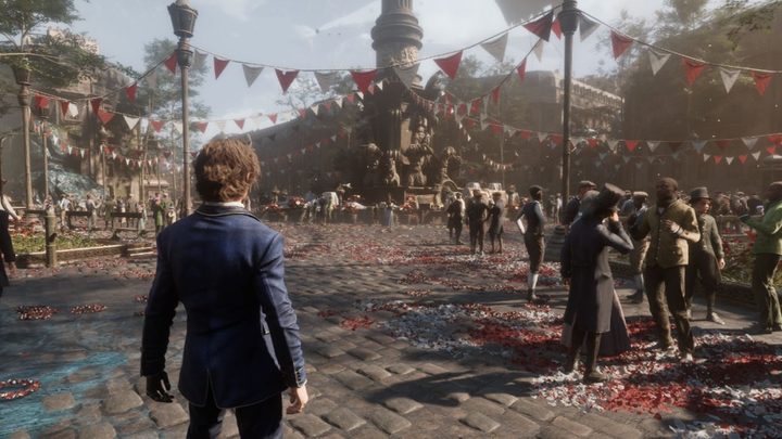 A man in a blue suit stands on a cobblestone street in the midst of a celebration