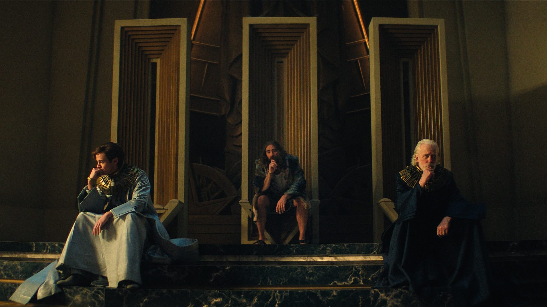 Three men sit on steps and ponder in Foundation.