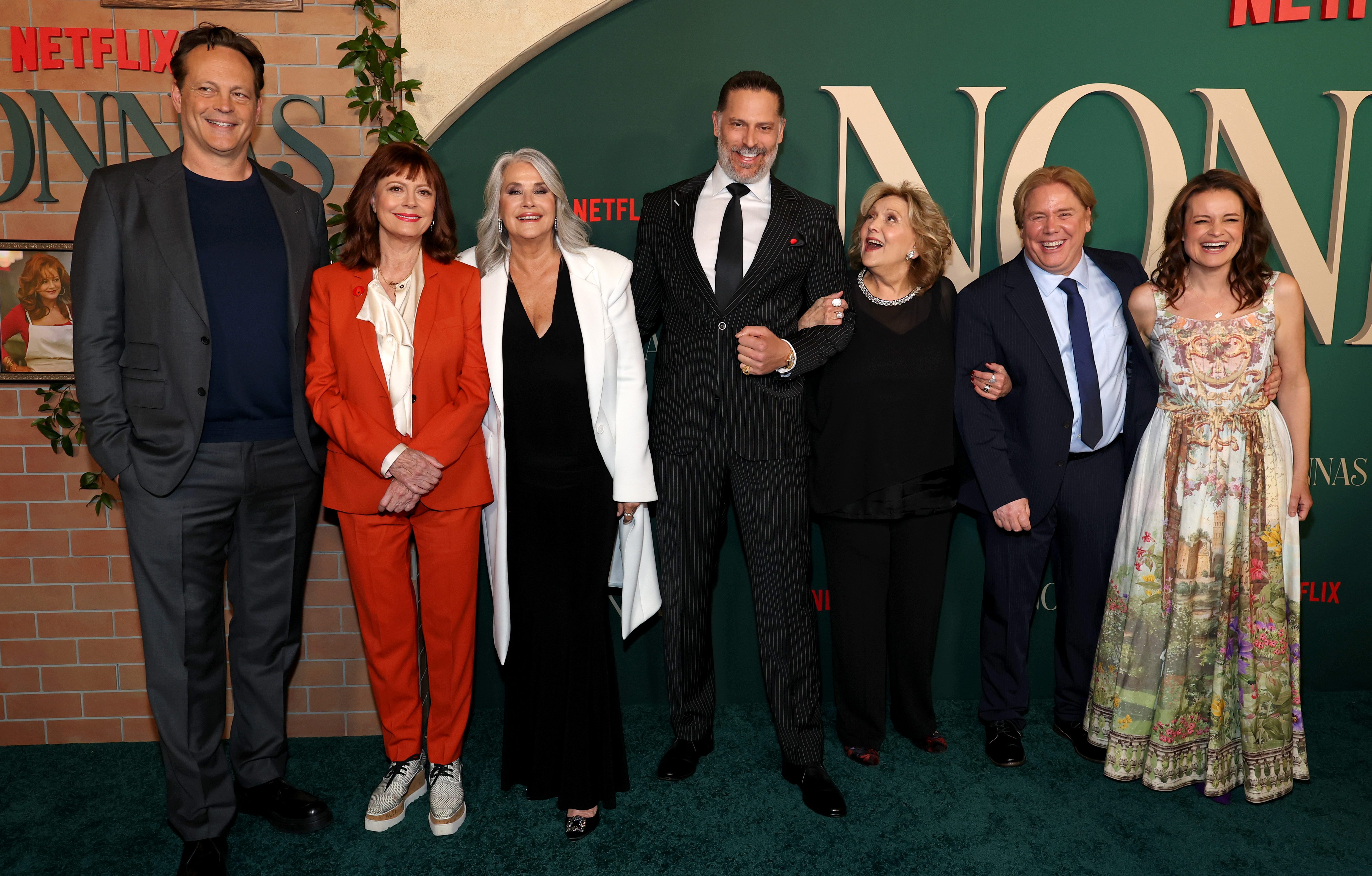 A group of people pose on a red carpet for Nonnas.