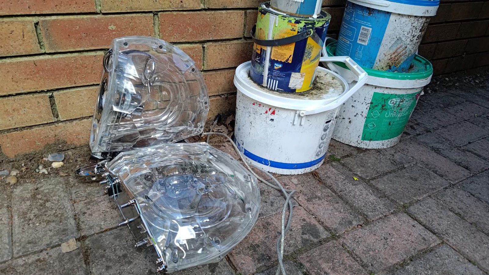 PC speakers outside by some paint tins.