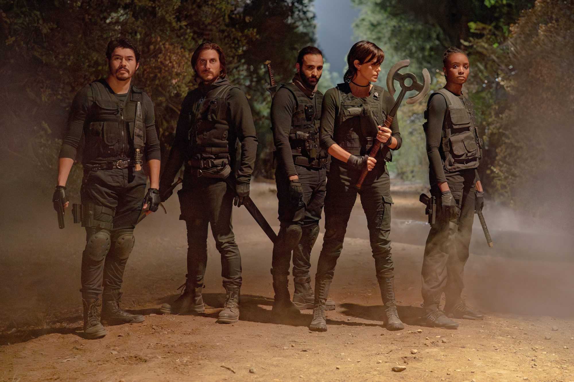 A group of soldiers stand in the dirt in The Old Guard 2.