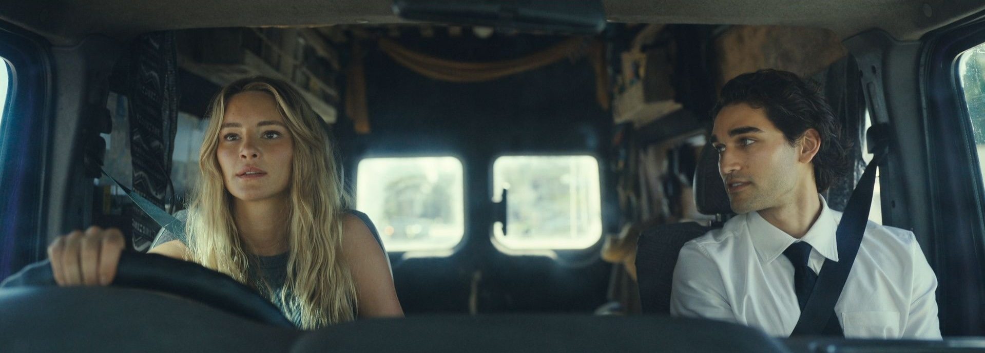 A woman and man sit in the front seat of a car.
