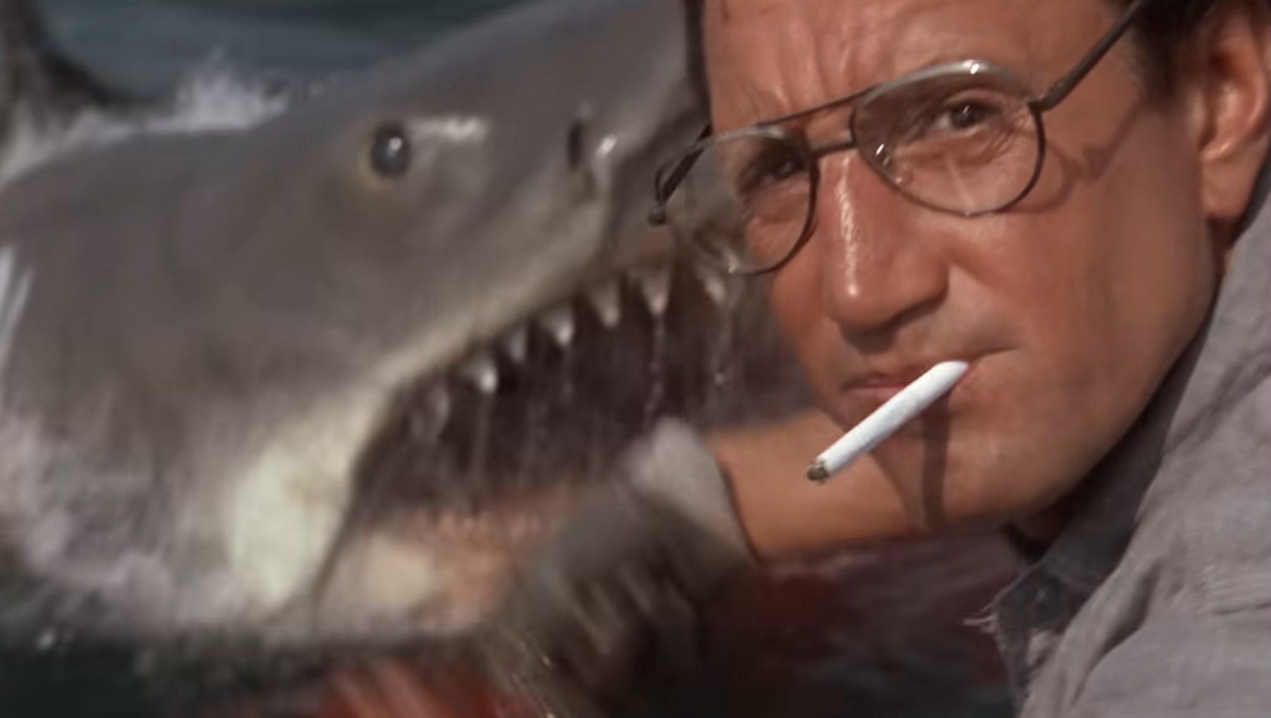 Roy Scheider as Brody looking at the camera with a shark behind him in "Jaws."