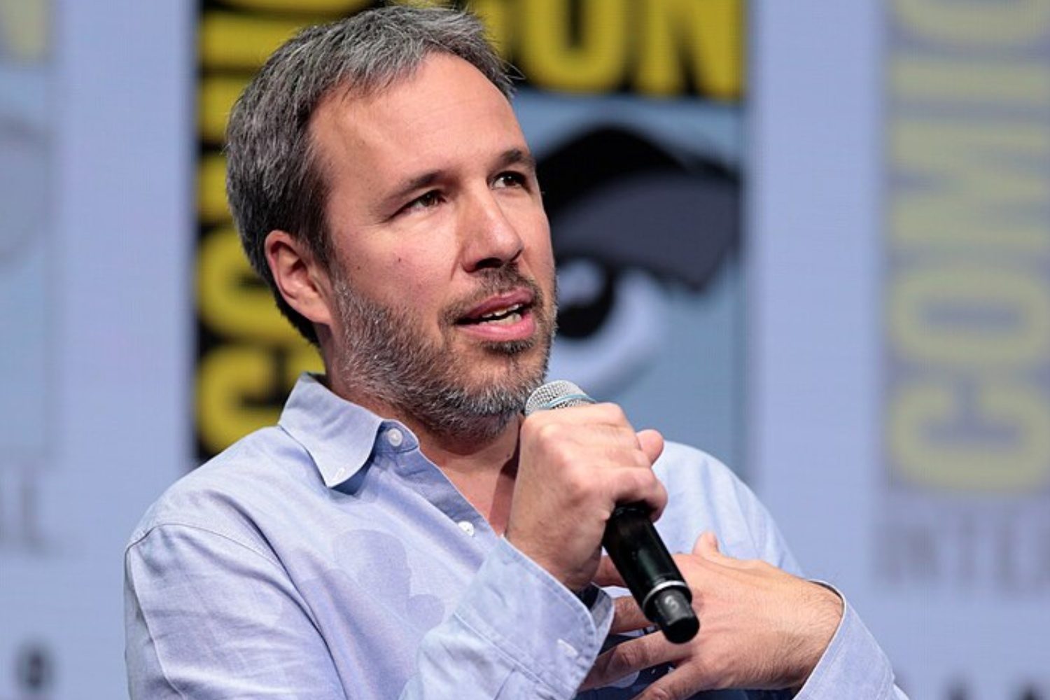 Denis Villeneuve holds a microphone.