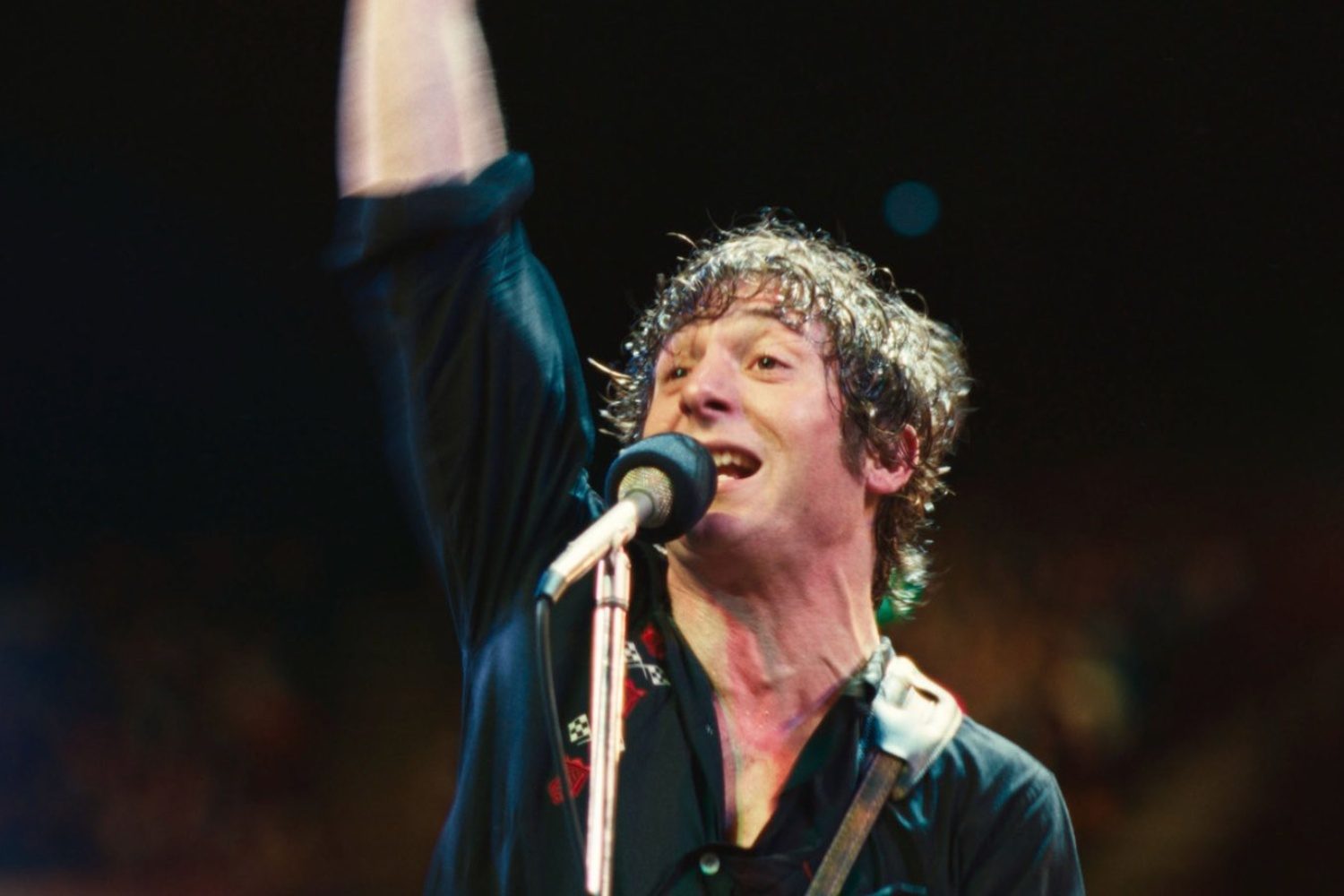 Jeremy Allen White puts his arm in the air and sings into a mic.