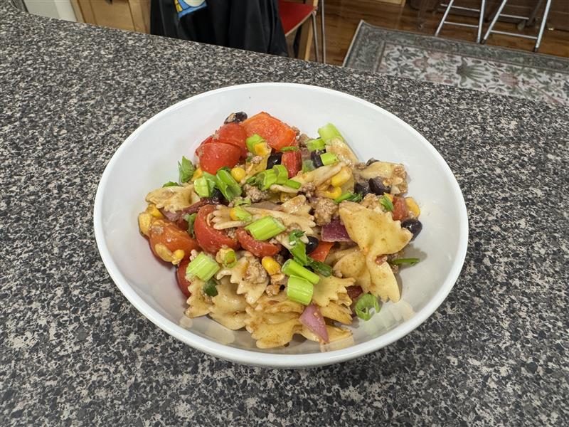 A pasta salad sits on a table in a bowl.