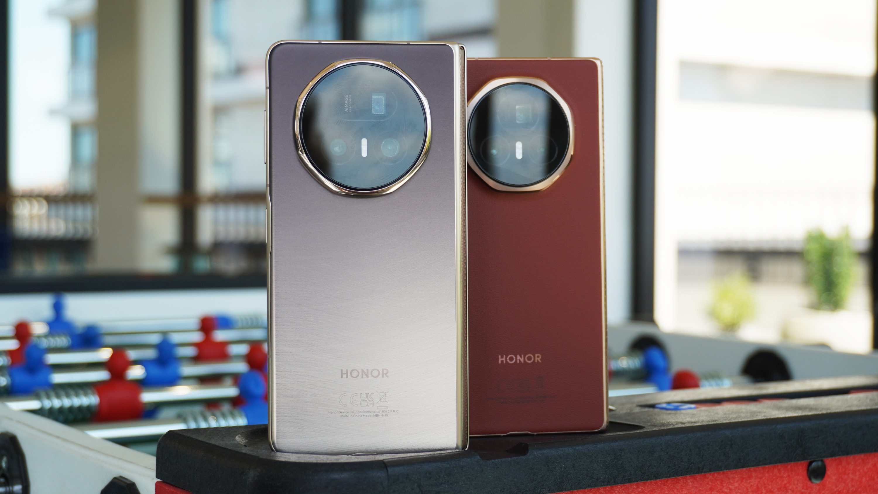 The Magic V5 and Magic V3 foldable phones standing on a foosball table