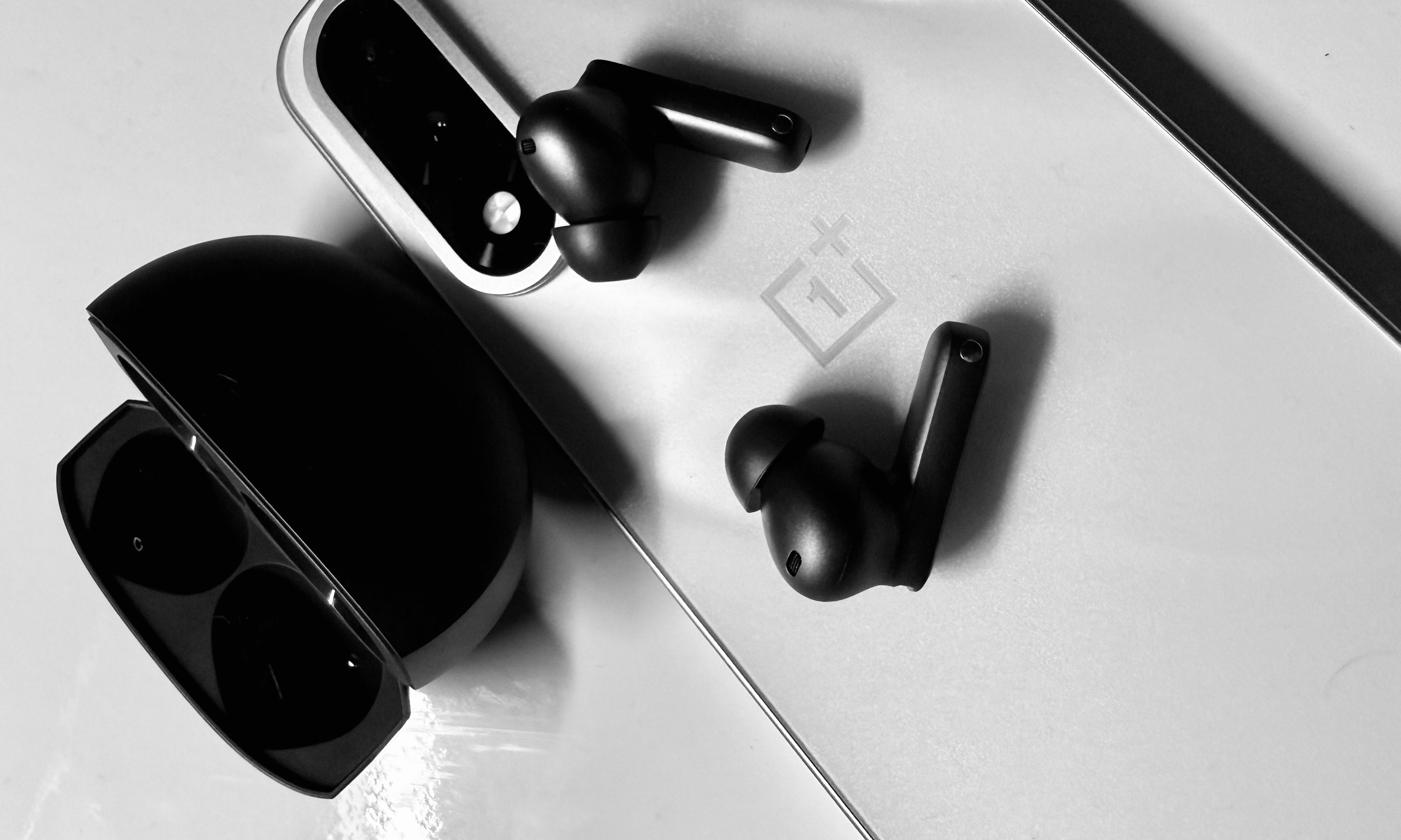 OnePlus Buds 4 earbuds above a phone.