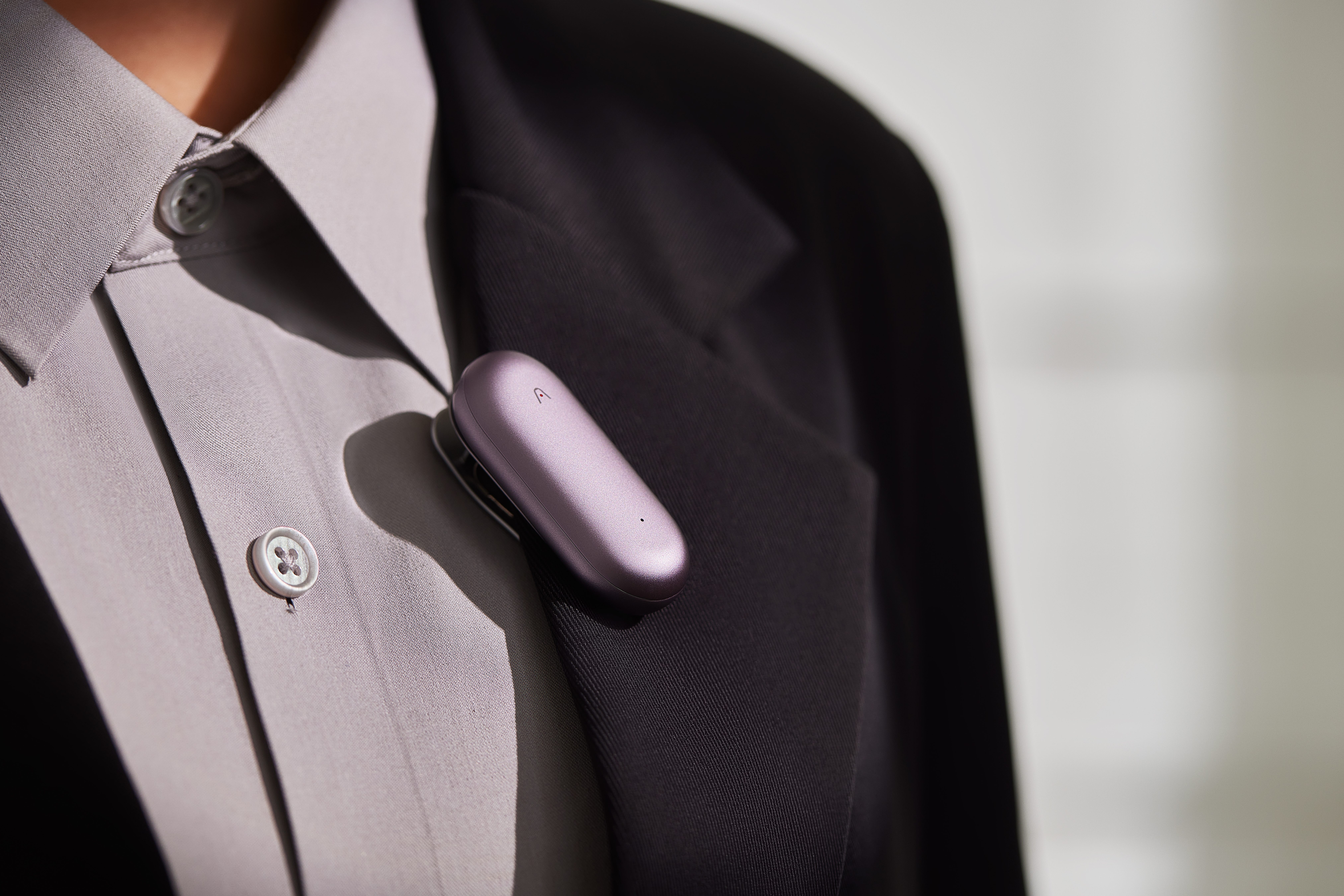 A man wearing a Plaud NotePin on this suit.