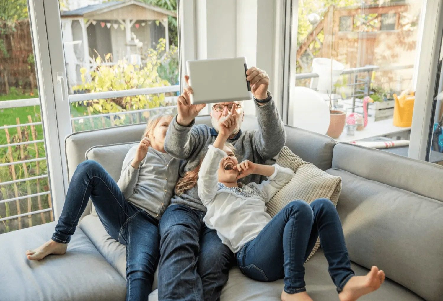 grandfather on couch with grandkids looking at a tablet