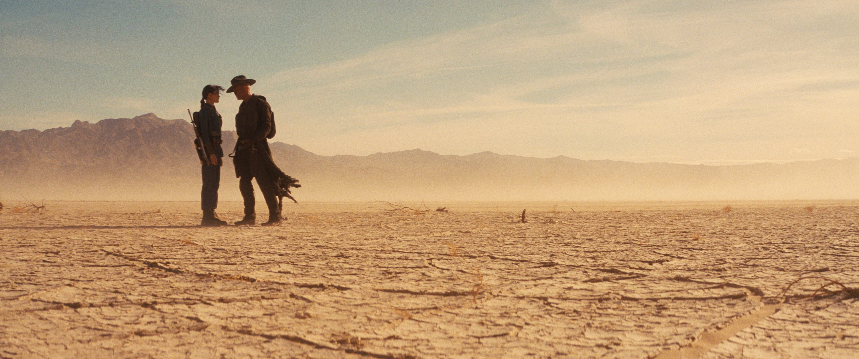 A man and woman stand in the desert.