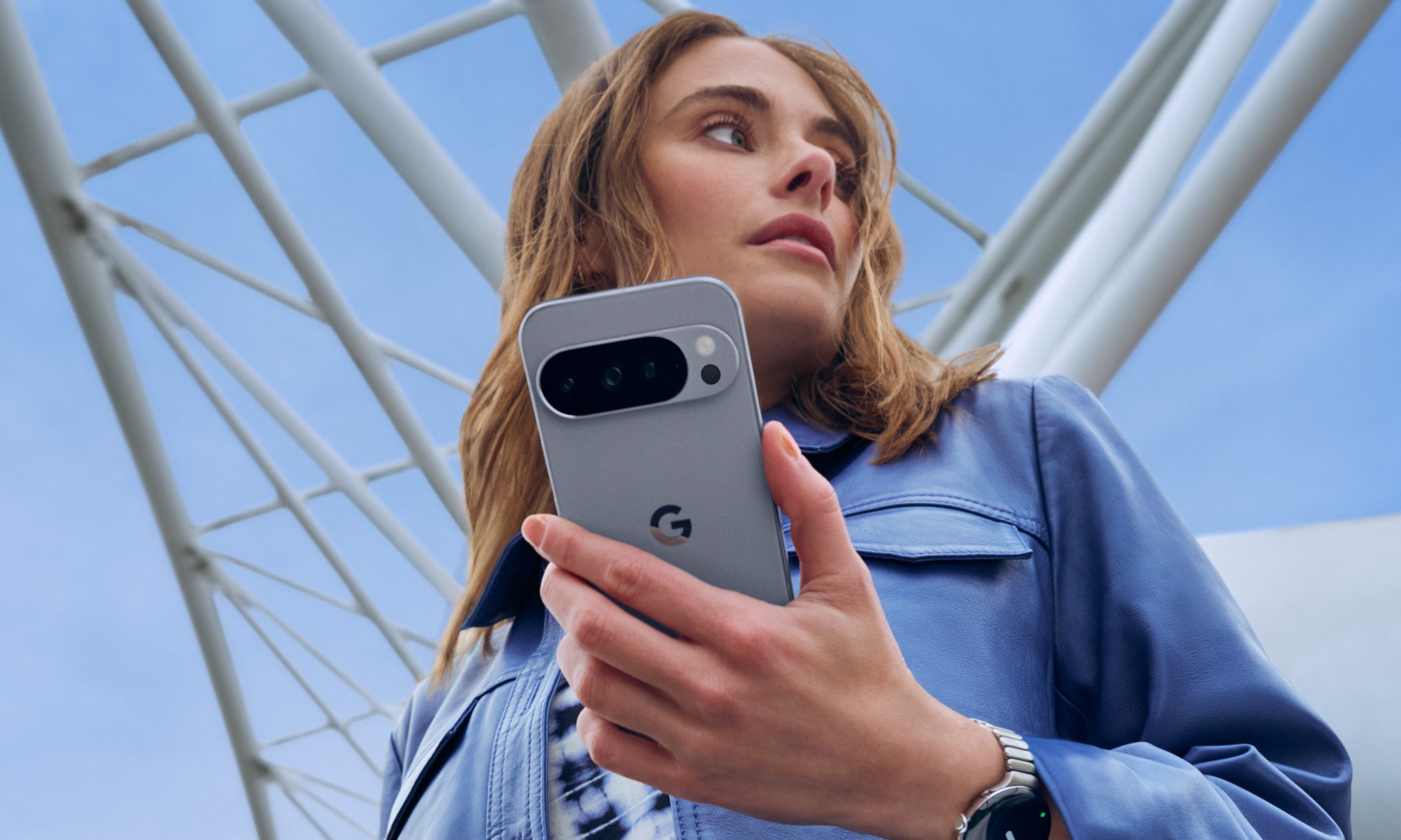 A person in a blue jacket holding the Pixel 10 Pro in one hand