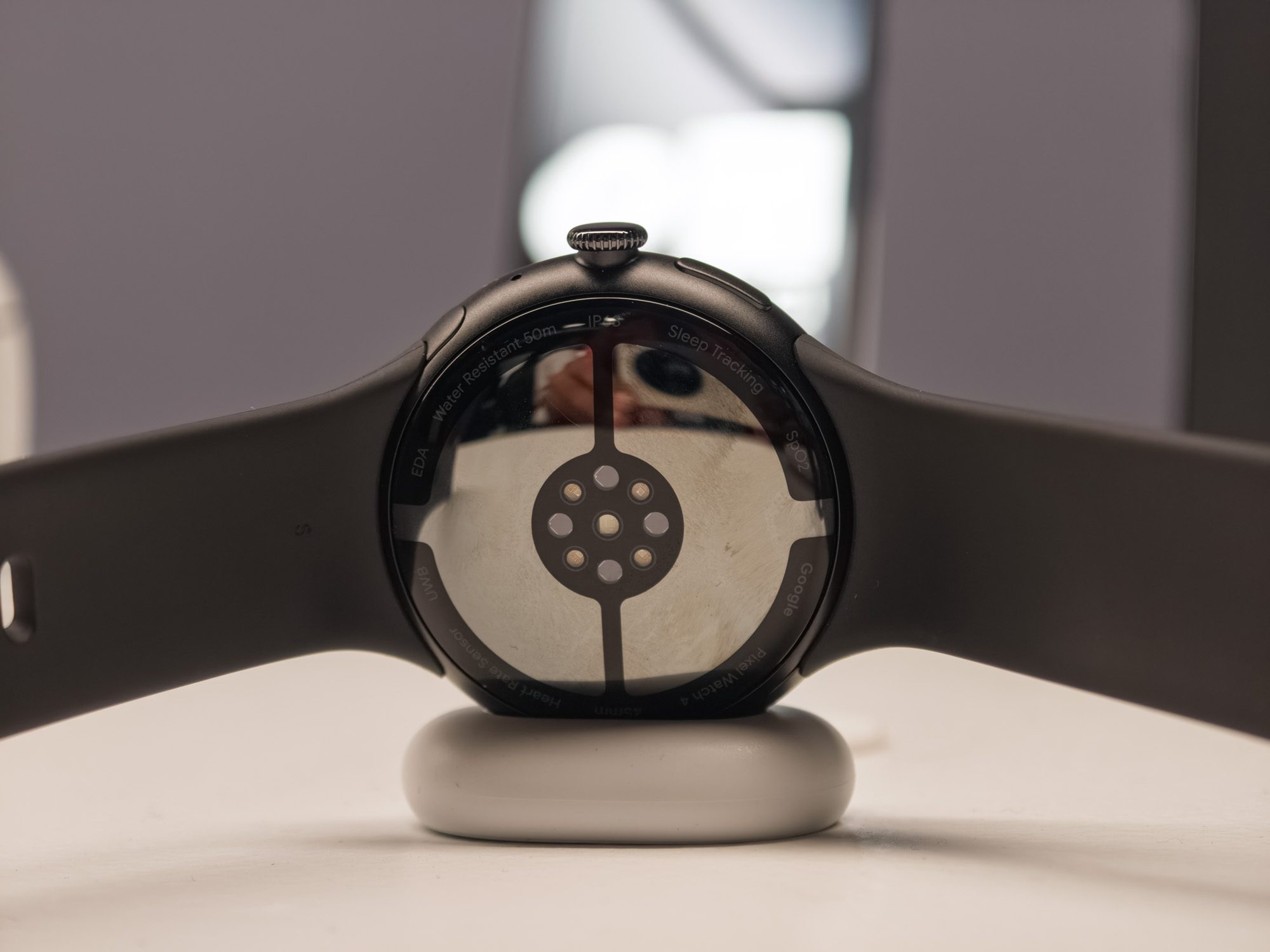Google Pixel Watch 4 sensors in black on a charger