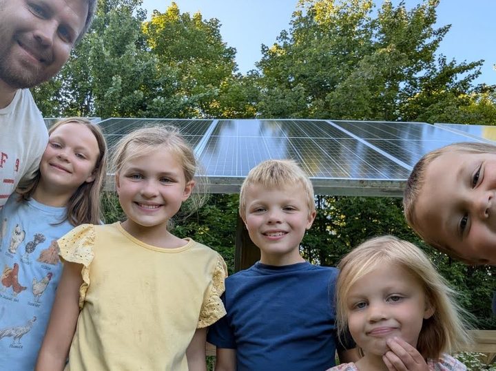 Man with his 5 kids next to solar panels