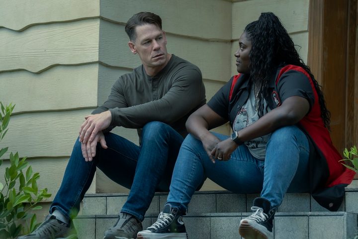 John Cena sits down with Danielle Brooks on a step in Peacemaker.