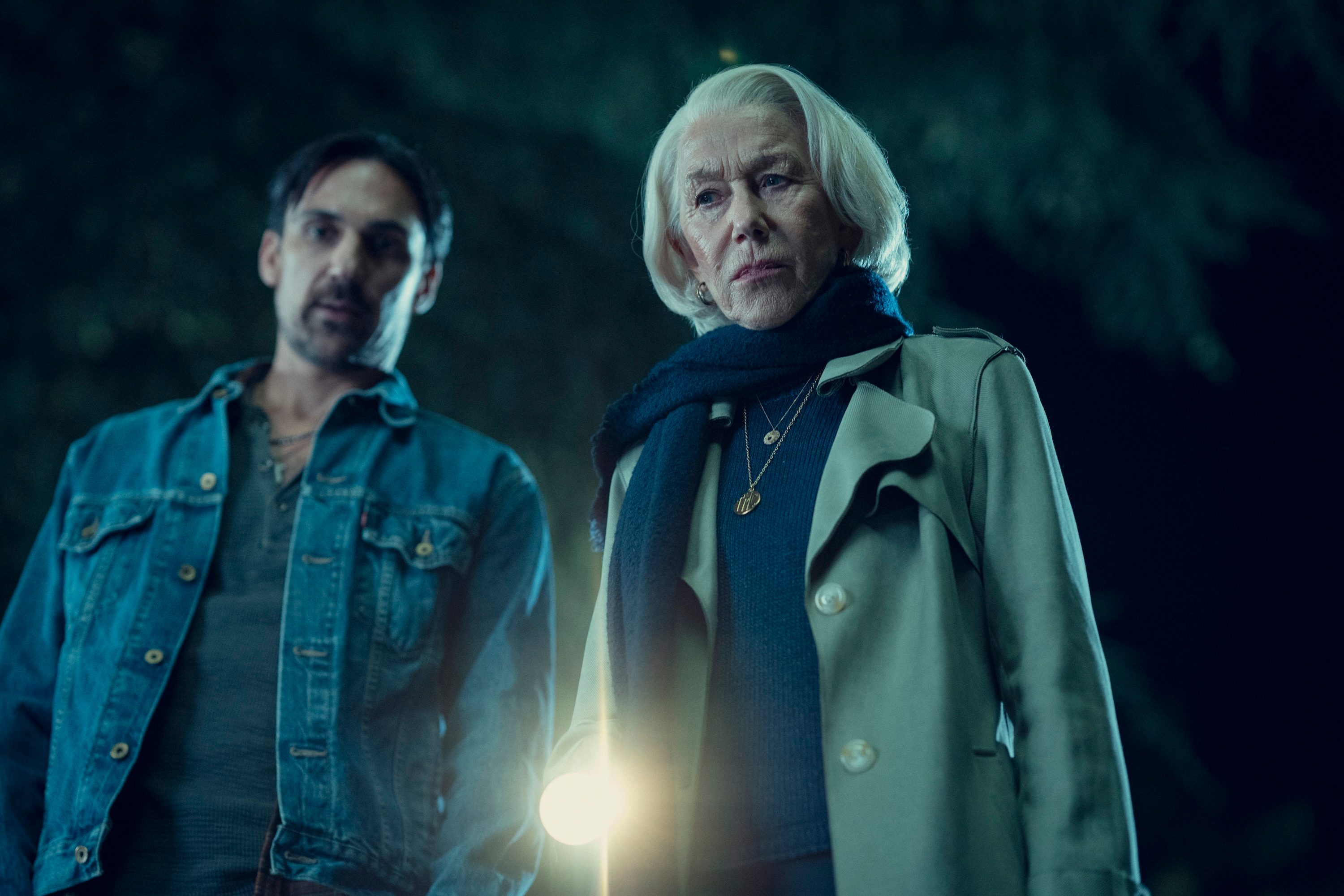 A woman points a flashlight down with a man next to her.