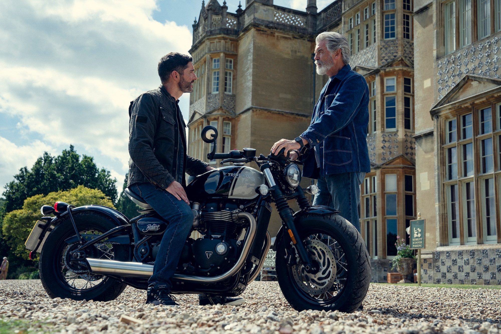 A man sits on a motorcycle and looks at another man.
