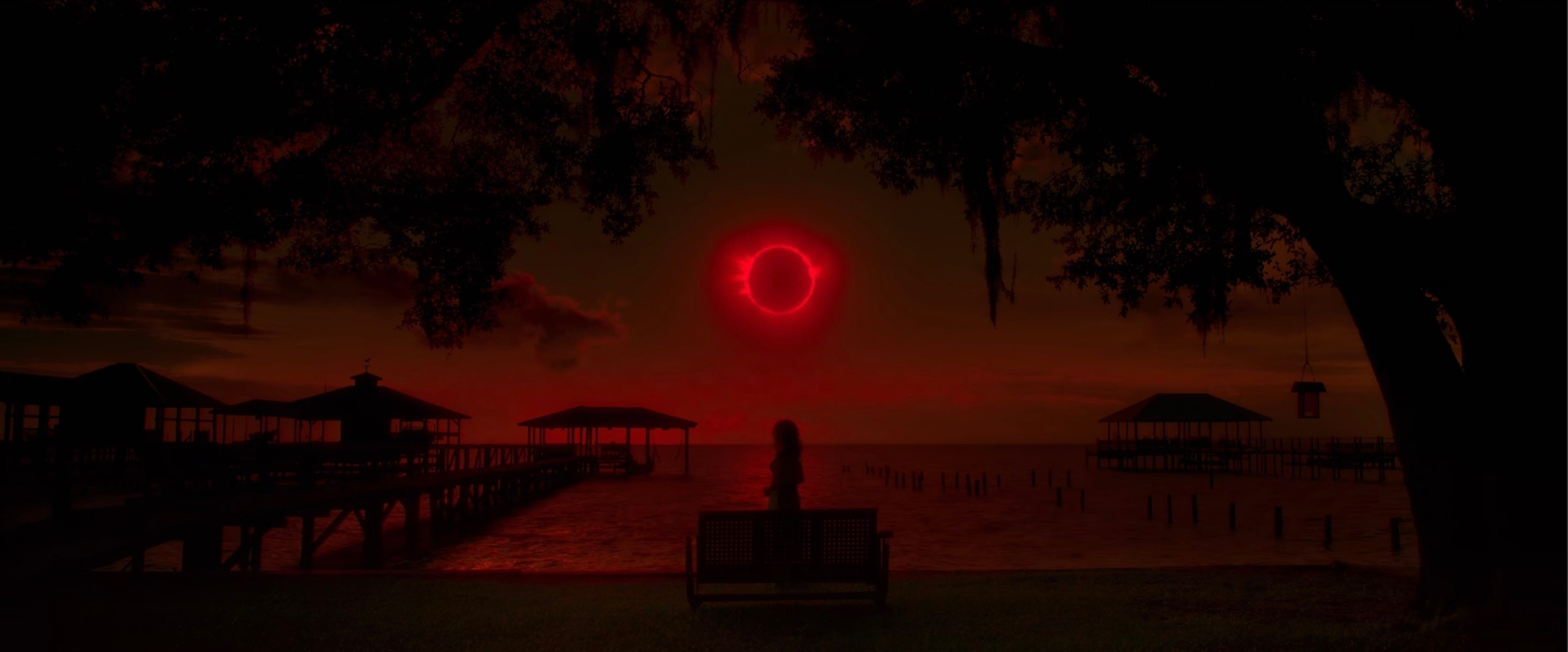Carla Gugino standing by a lake in front of a solar eclipse in Gerald's Game.