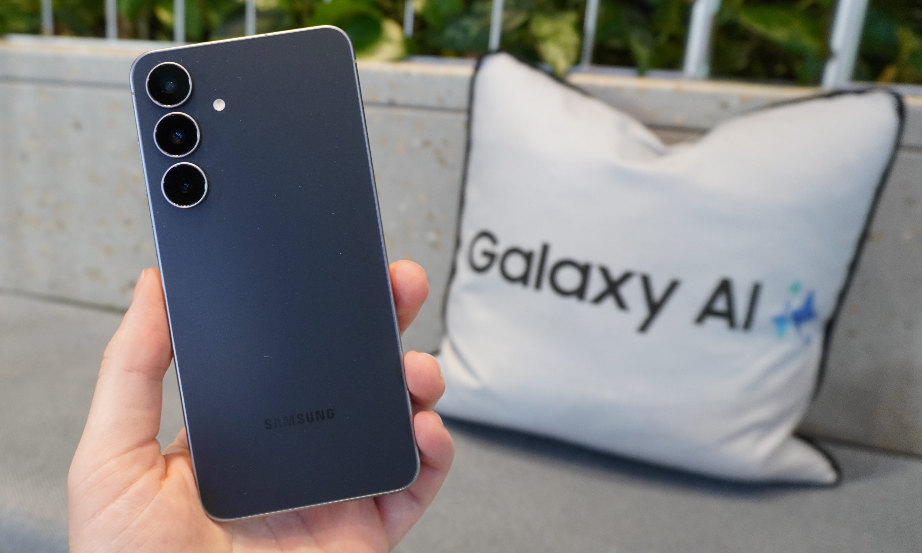 The Galaxy S25 FE held in front of a white cushion with the words 'Galaxy AI' written on it