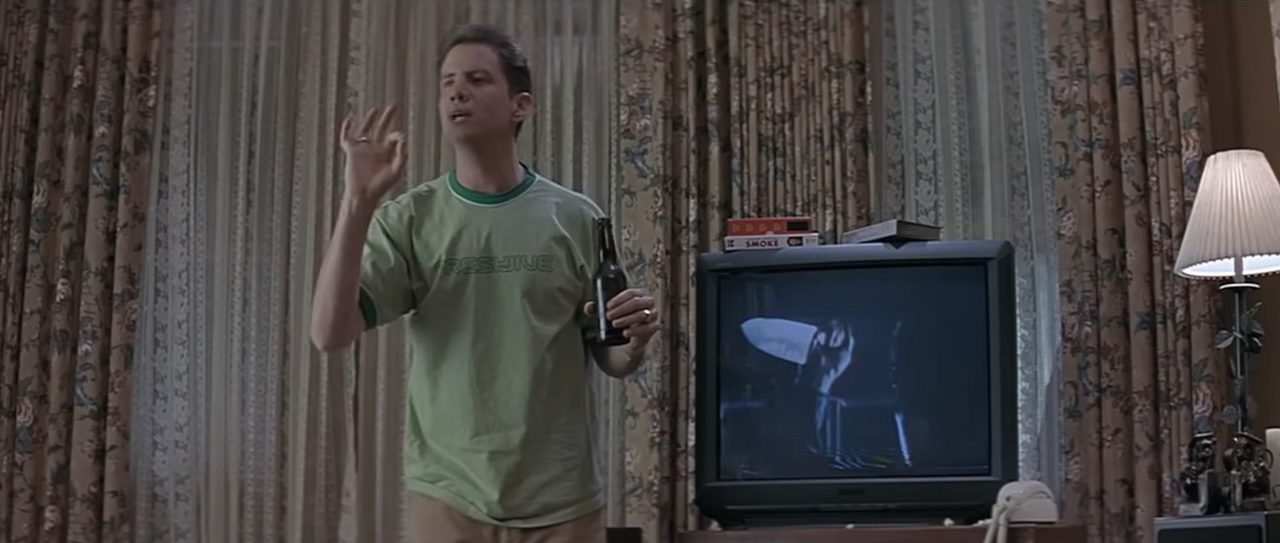 Jamie Kennedy talking next to a TV in Scream (1996).