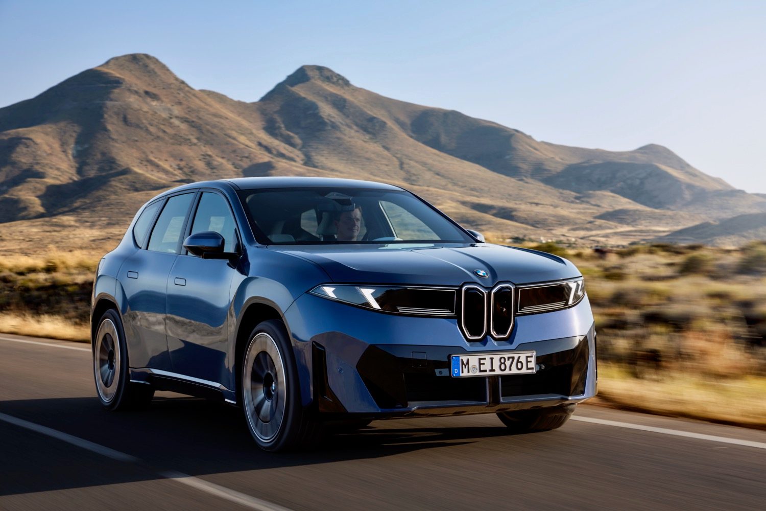 A BMW iX3 driving through a desert.
