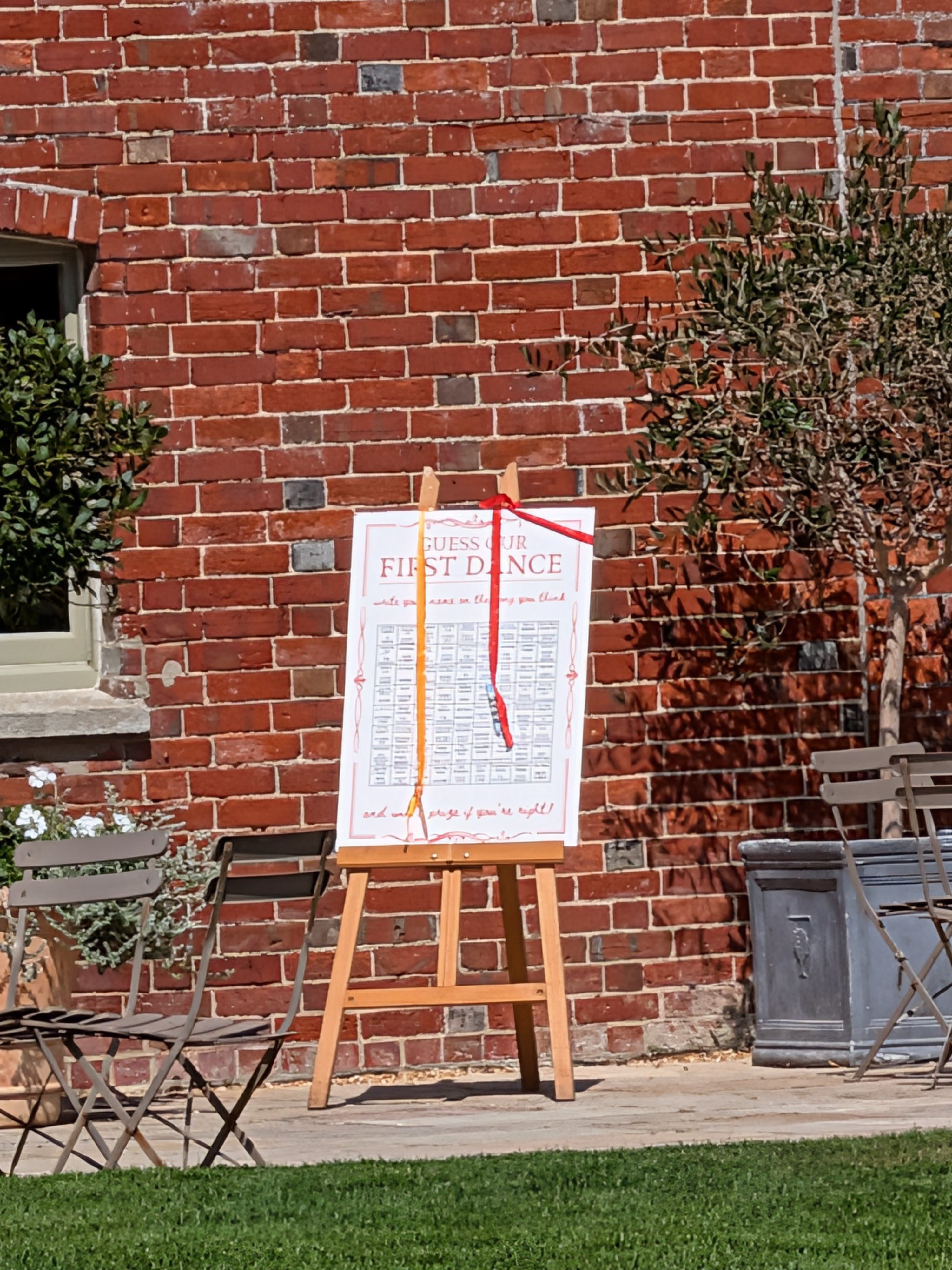 An a-board with a wedding poster on it, in front of a red brick wall