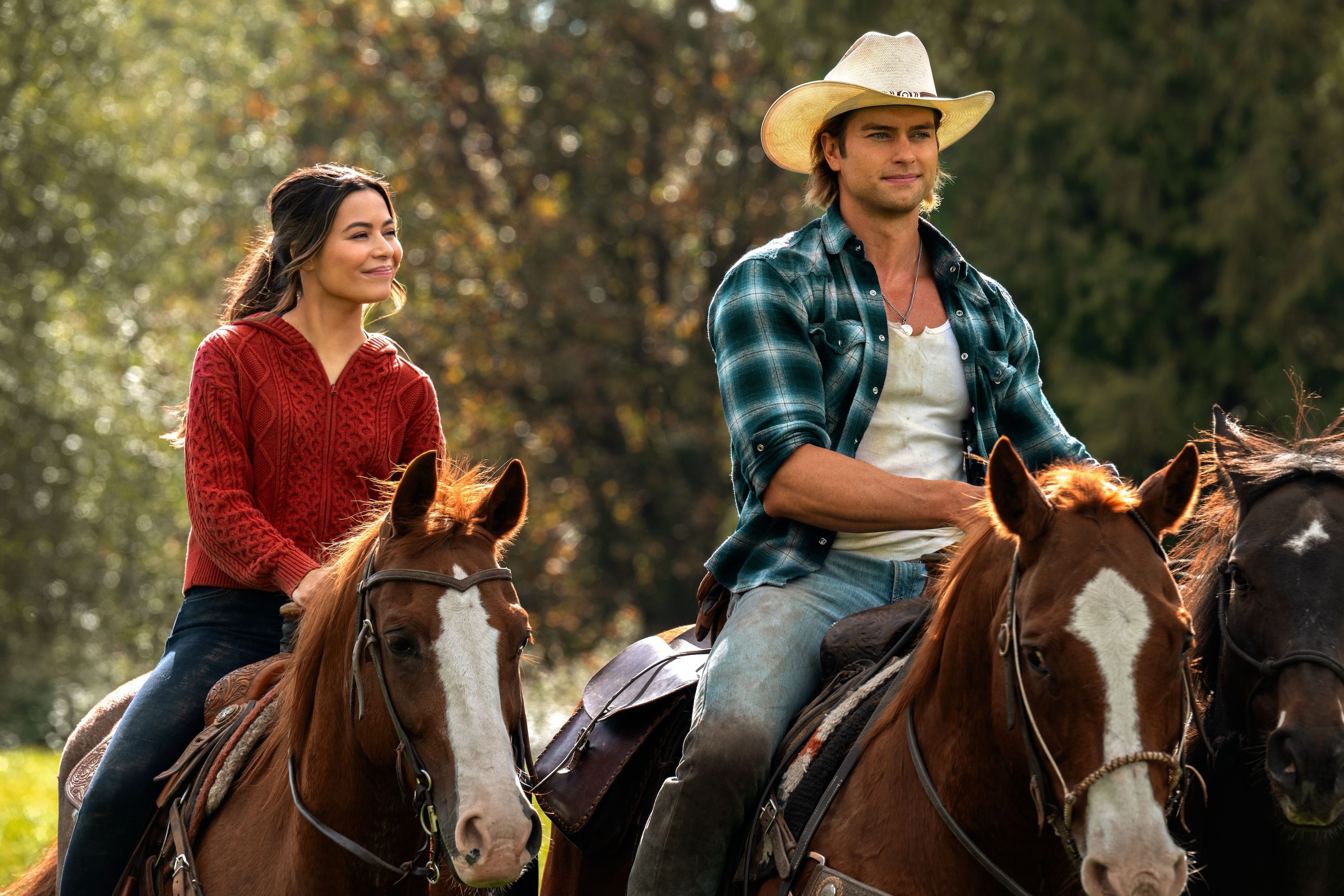 A woman and a man sit on horses.