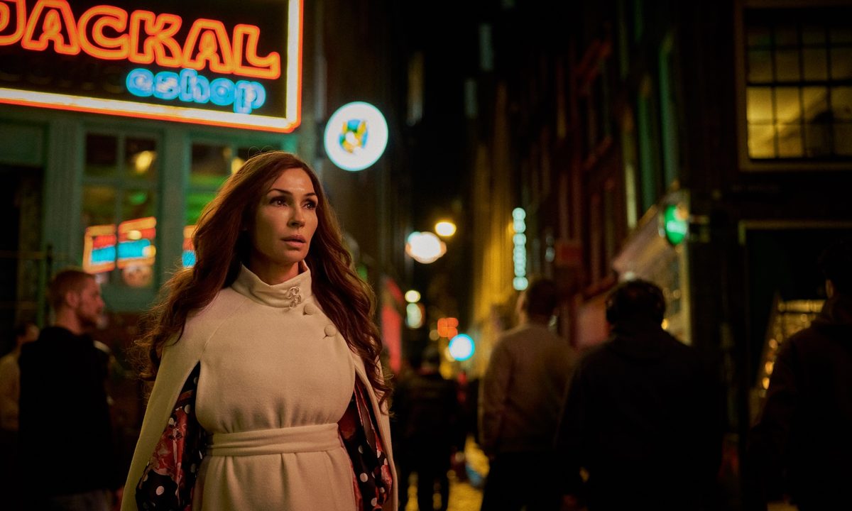 Famke Janssen walks and stares.