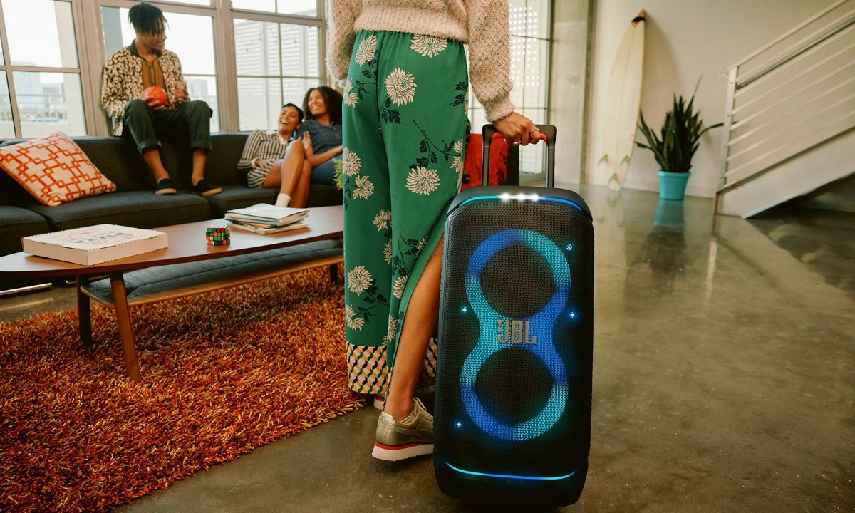 A woman transporting the JBL PartyBox Stage 320 portable wireless party speaker.