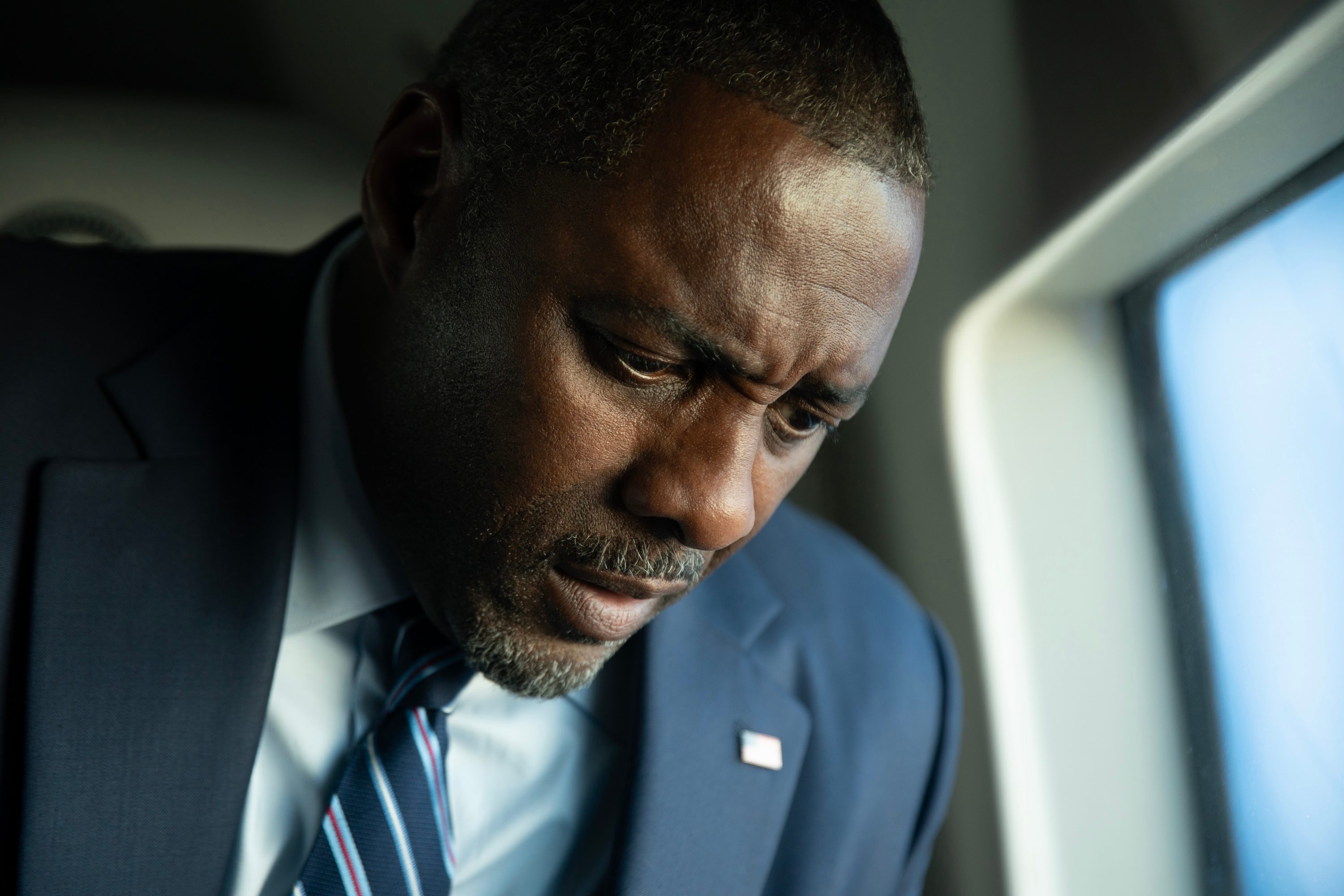A man stares down by a window.