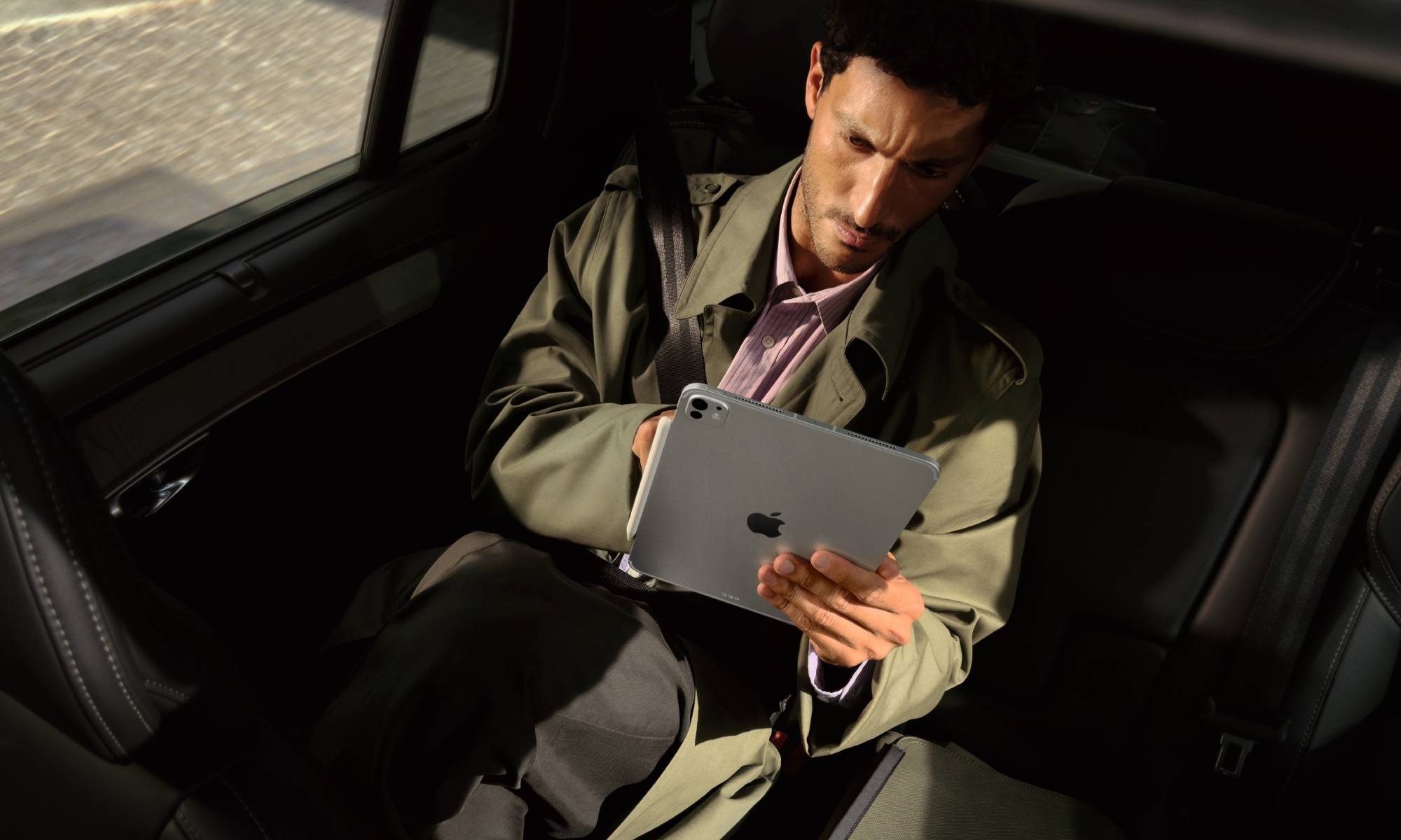 Person in the backseat of a car using an iPad Pro with Apple's M5 chip.