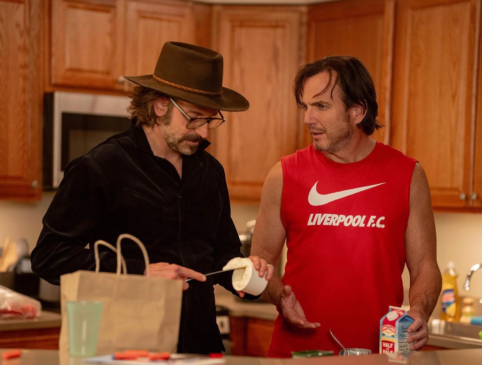 Two men stand next to each other in the kitchen.