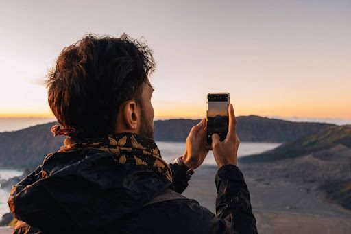 man taking a picture at sunset