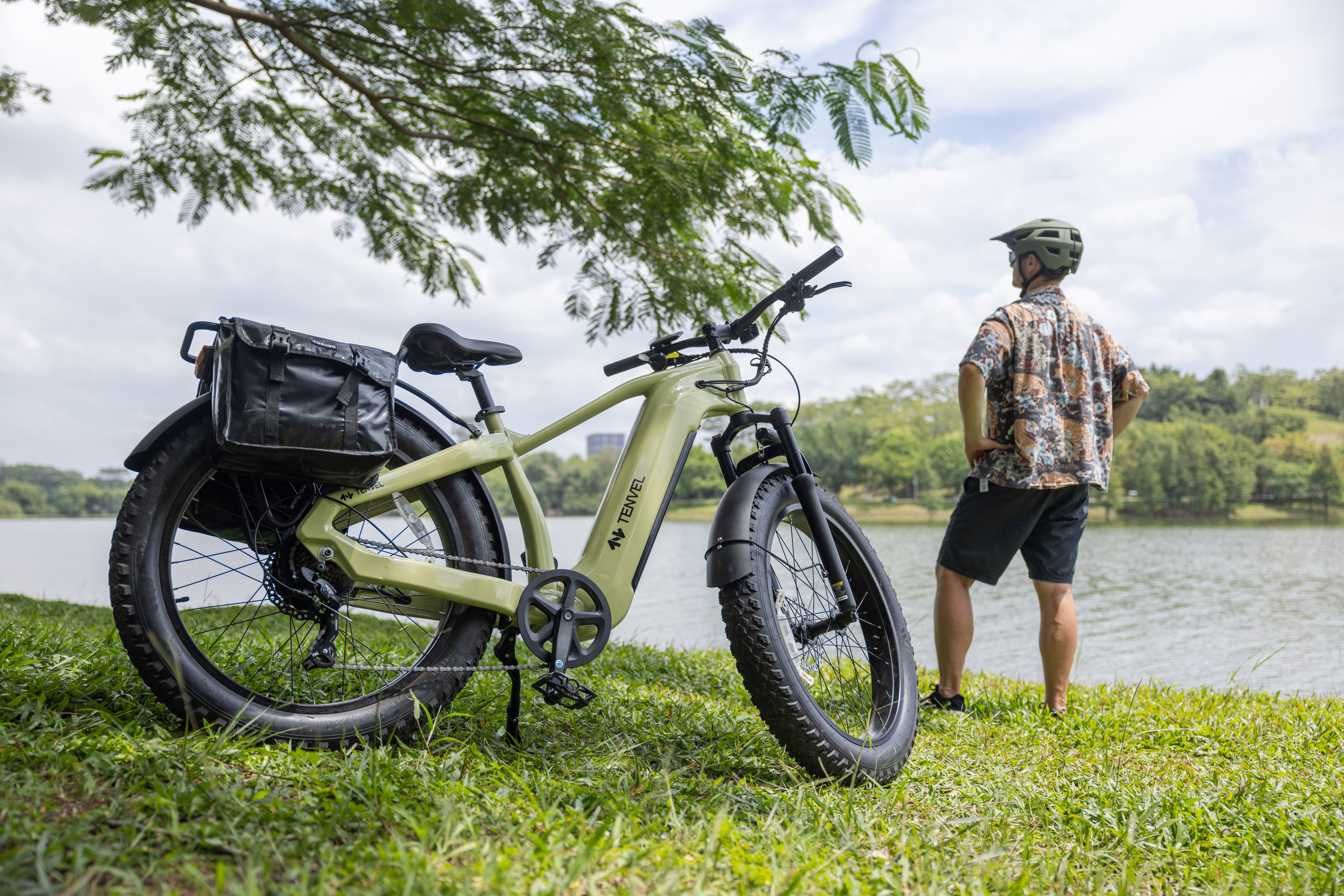 man looking over a body of water with his bike parked