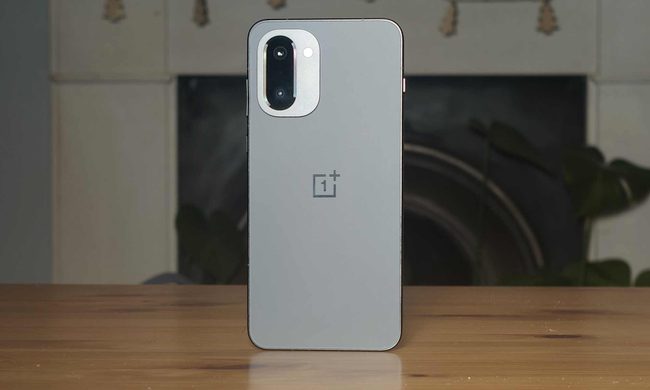 The rear of the OnePlus 15R, propped up on a wooden table.