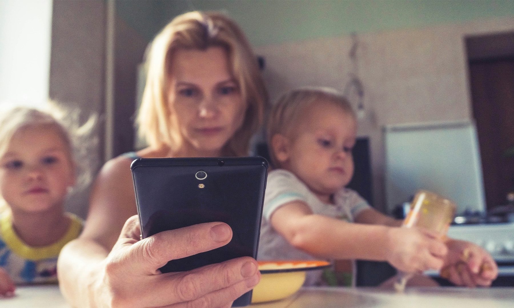 A woman uses smartphone while sitting with children