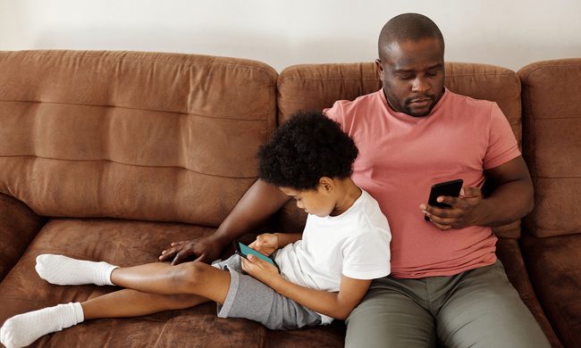 Father and son bonding over smartphones while relaxing on a comfortable couch at home